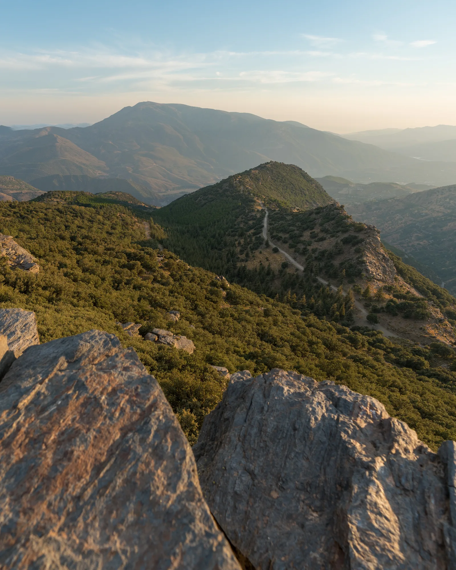 Glassing the Spanish ridges from a rocky summit at golden hour