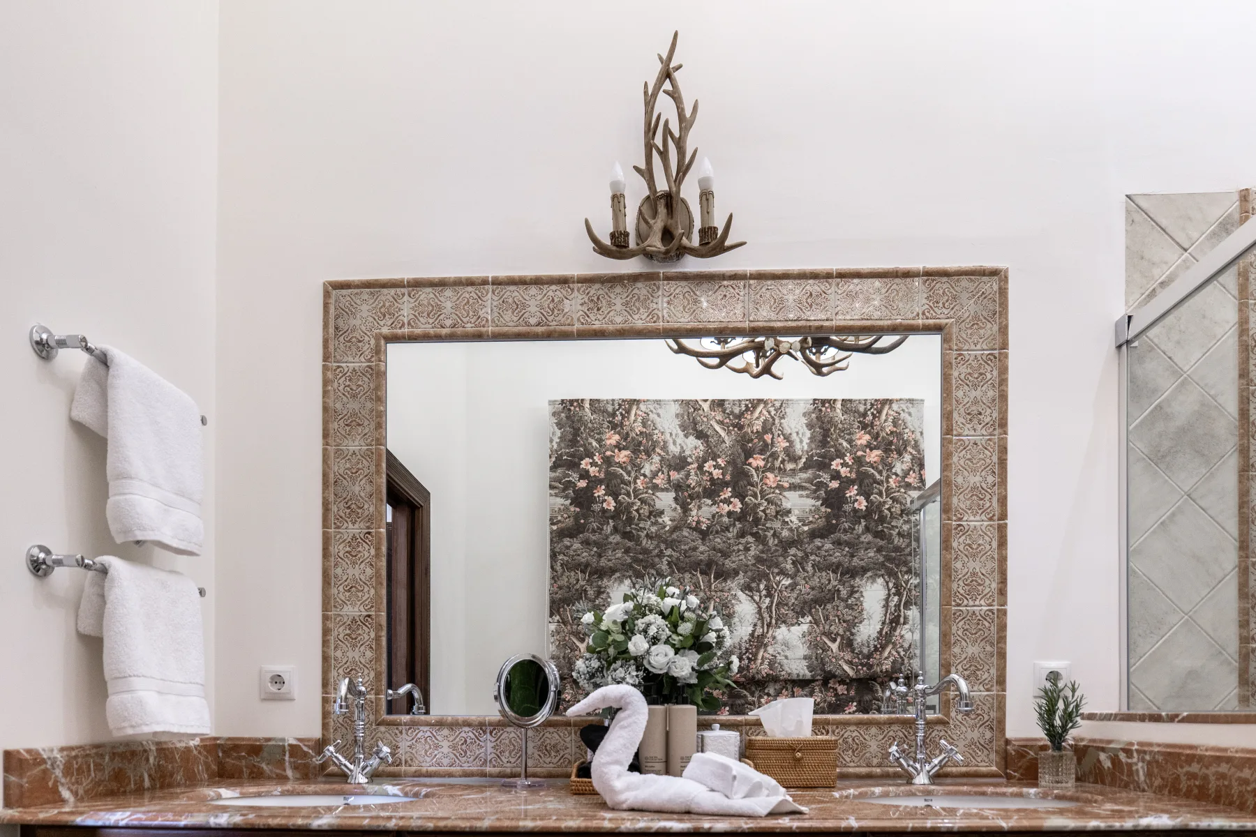 Twin basins in rose marble under a wide gilt-edged mirror