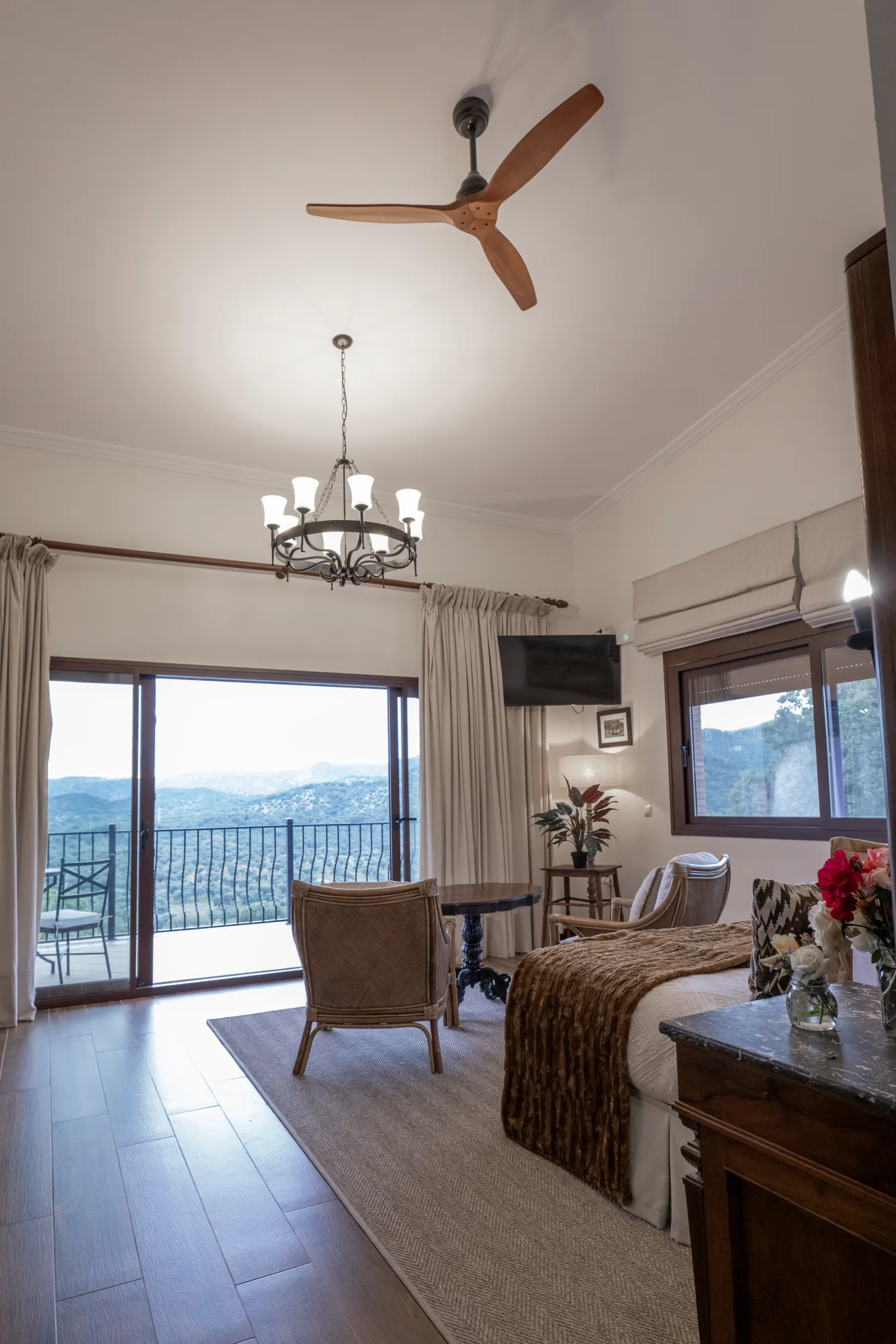 A lodge bedroom with glass doors opening onto a private balcony and the sierra beyond