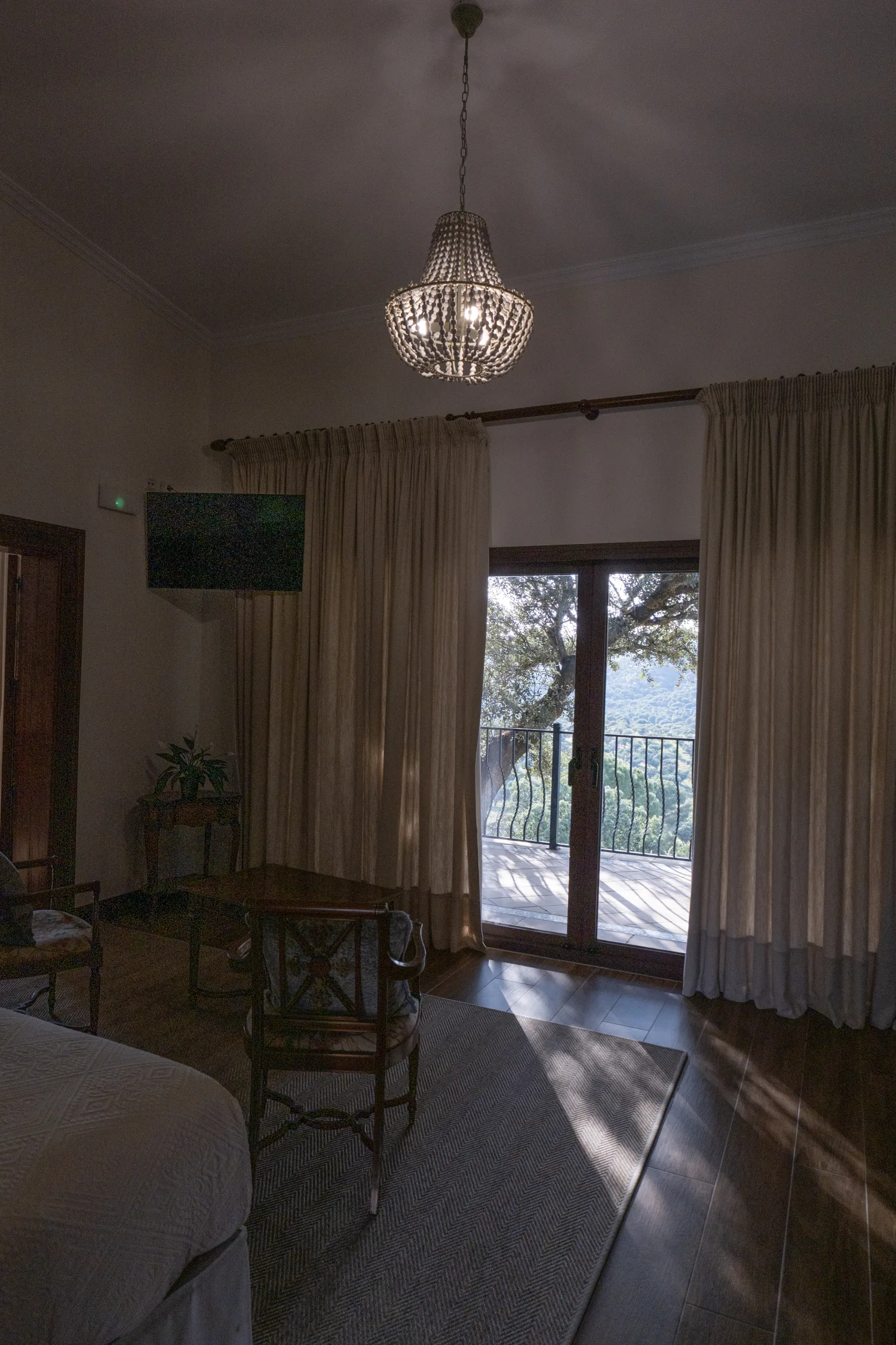 A lodge bedroom at dusk, glass doors open onto the terrace