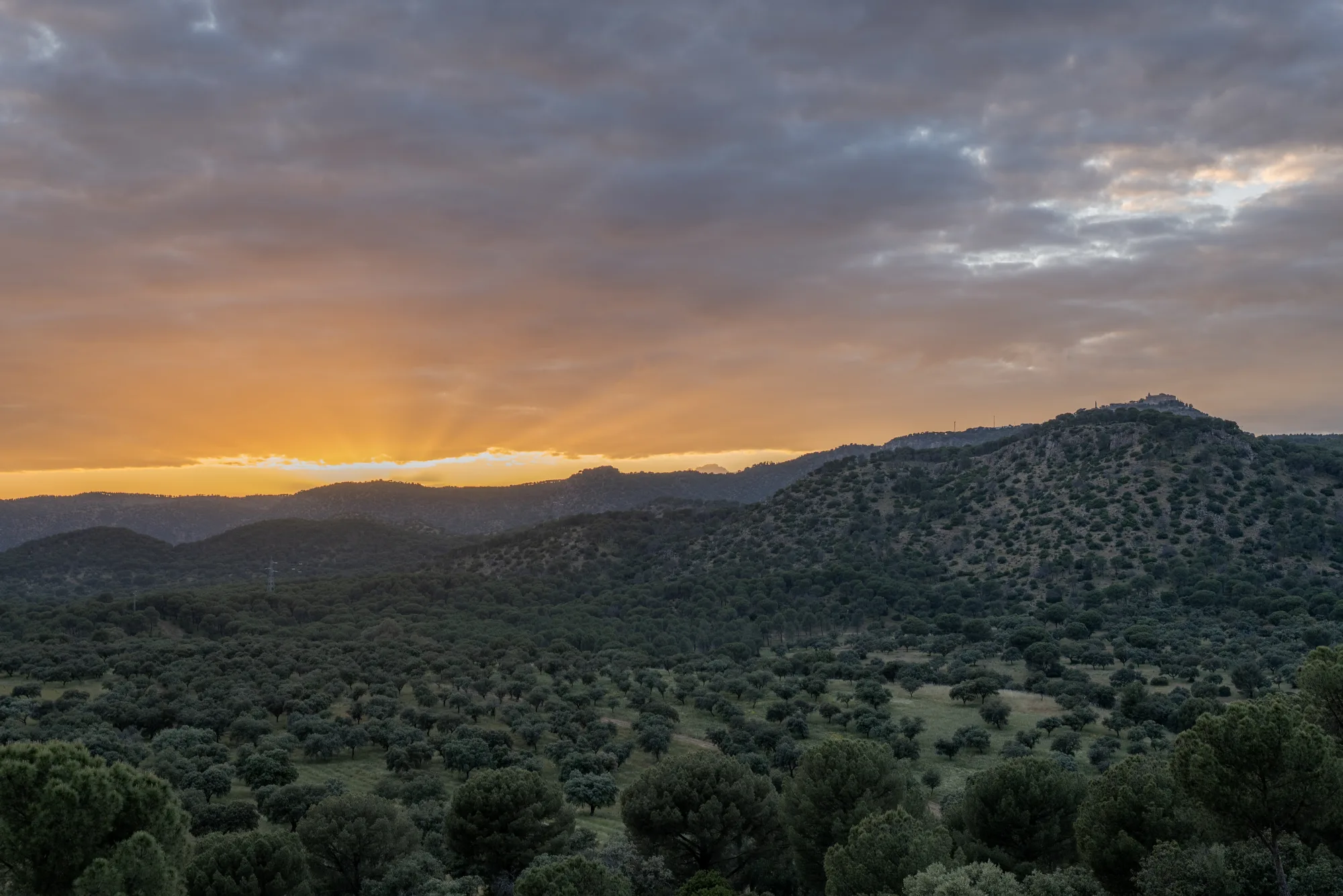 Sunset over the layered sierra ridgelines above the finca's dehesa