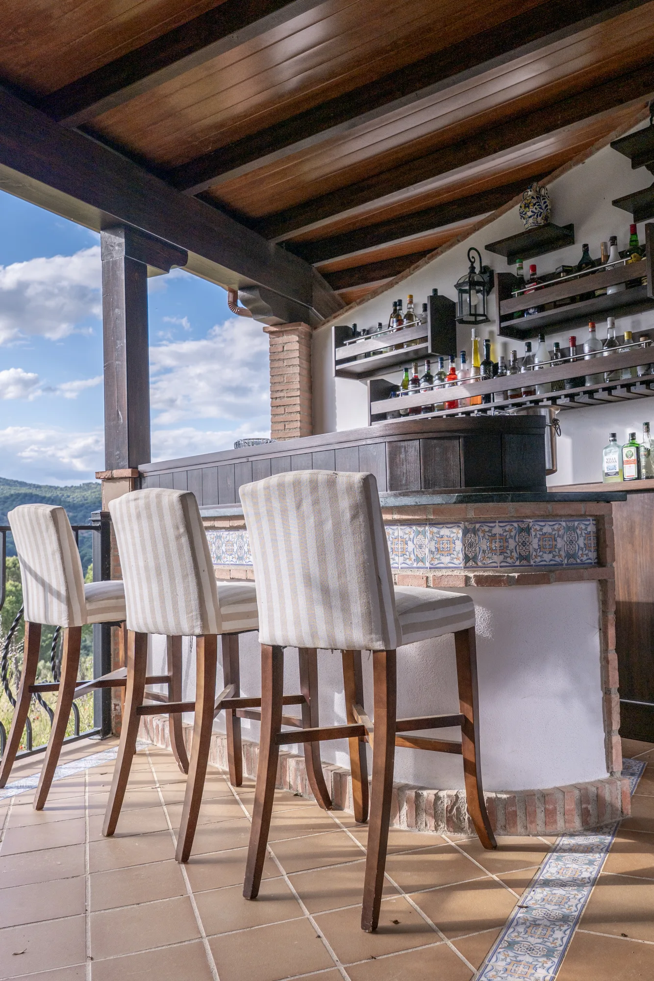 The terrace bar set for the evening, stools lined beneath the shelves