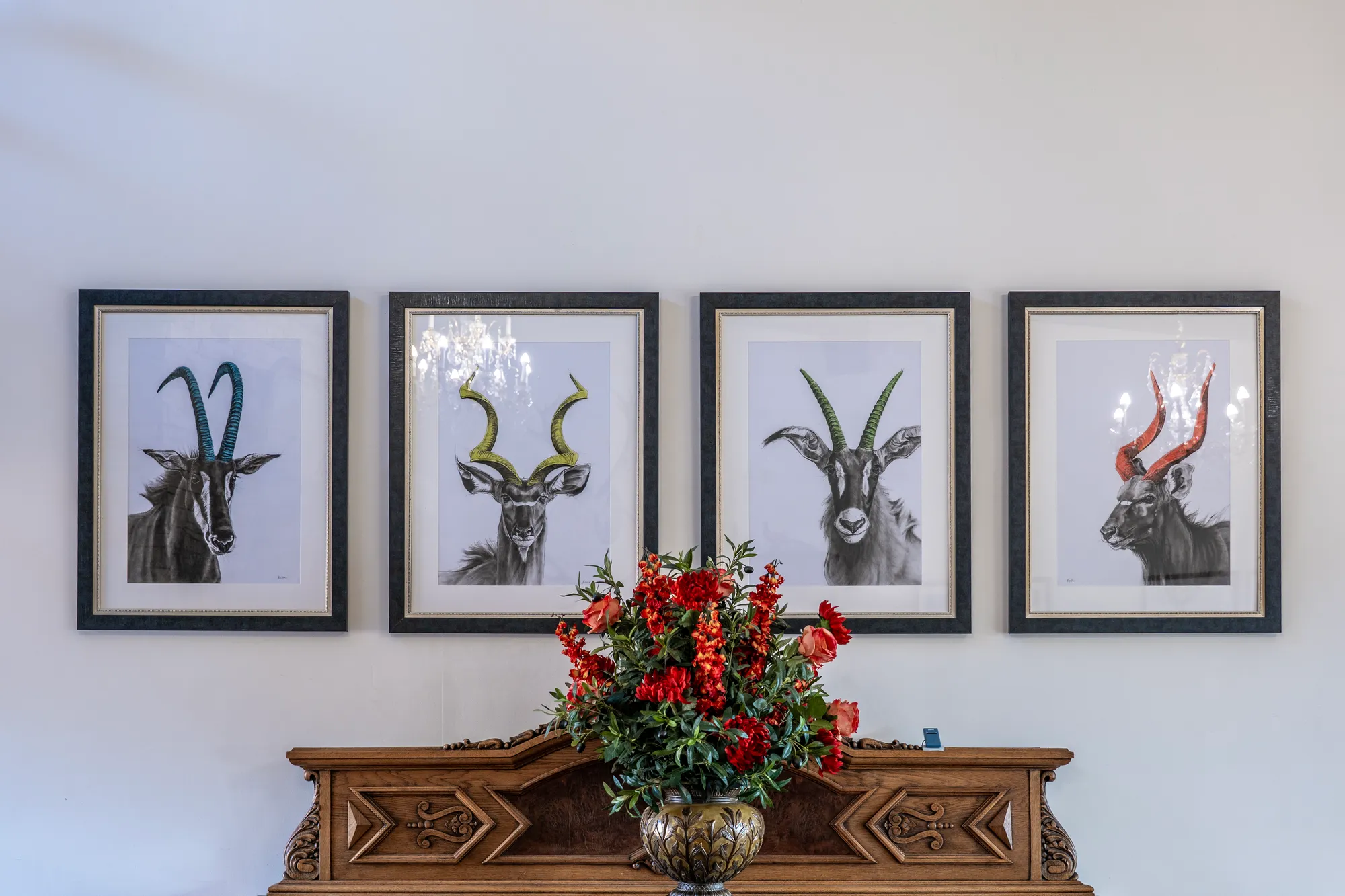Framed game studies above an antique console table
