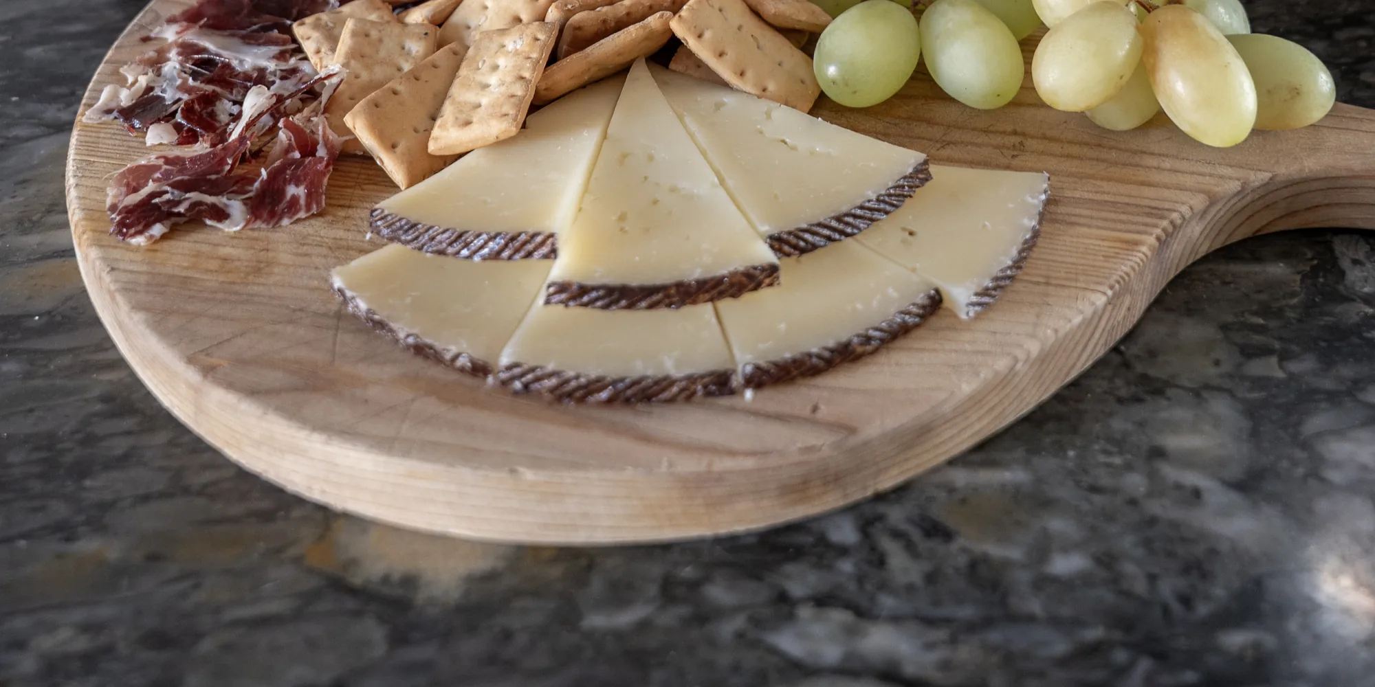 Manchego cheese, cured ham, crackers and grapes